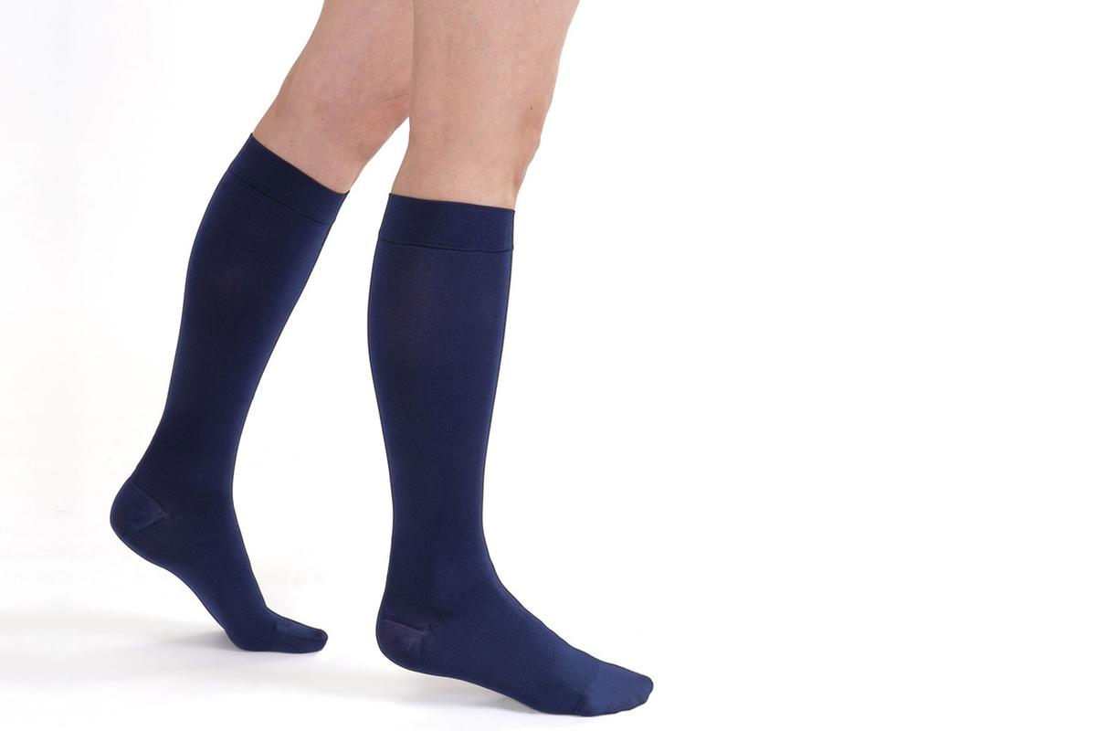 Beine mit Stützstrümpfen von SkySocks in dunkelblau. Die Beine sind bis zum Knie zu sehen.