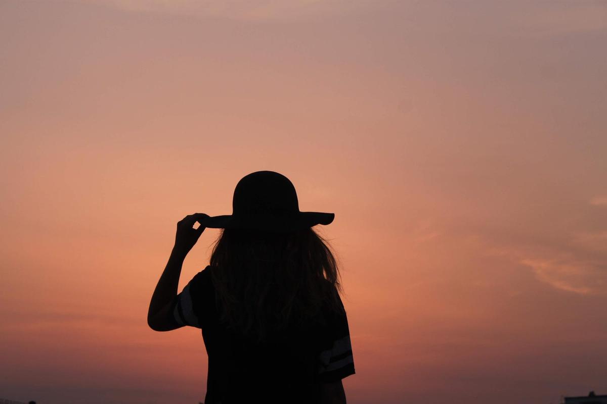 Frau mit Sonnenhut im Sonnenuntergang