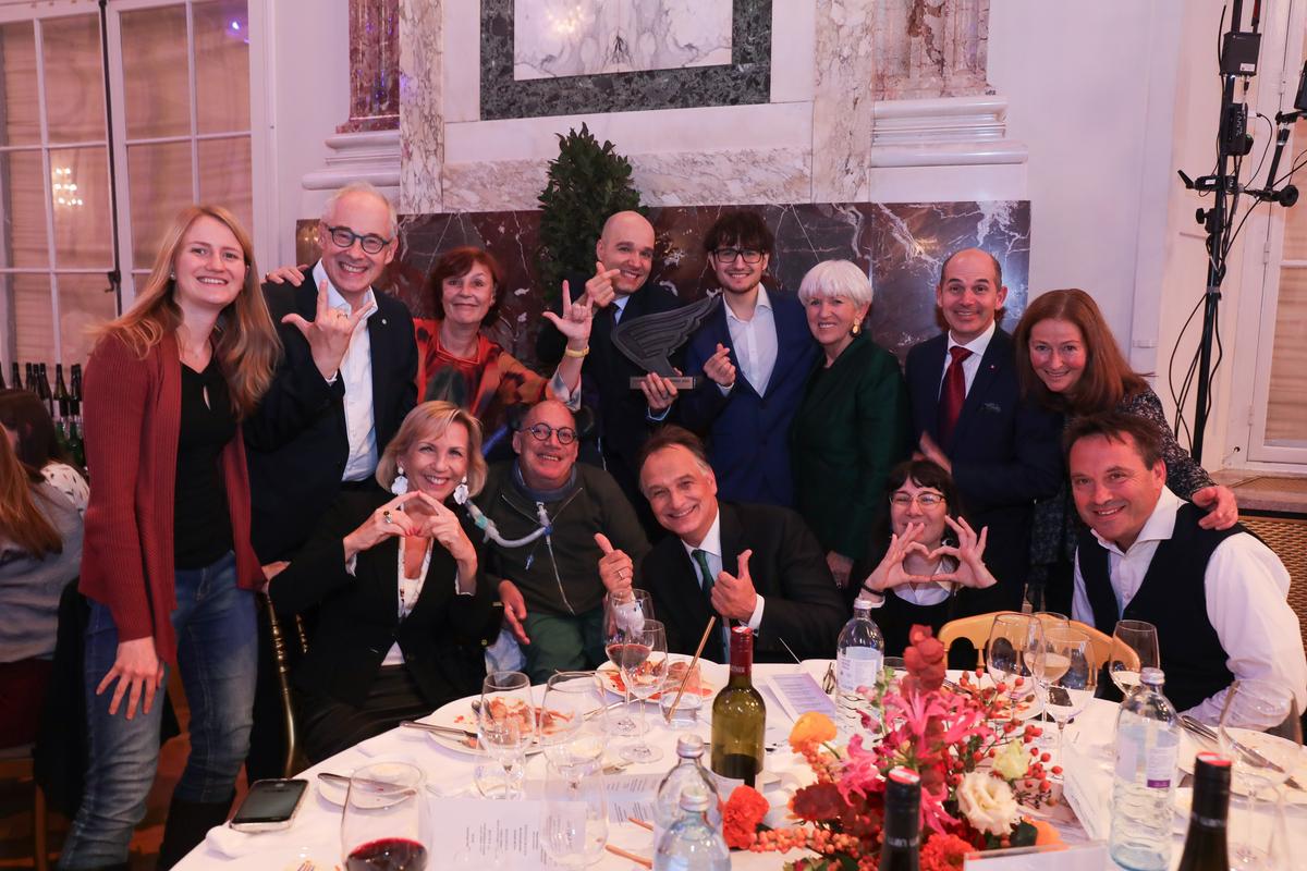 Karin Simonitsch und Sreco Dolanc mit Maria Rauch-Kallat, Franz-Joseph Huanigg und vielen weiteren Menschen vor einem weiß gedeckten Tisch.