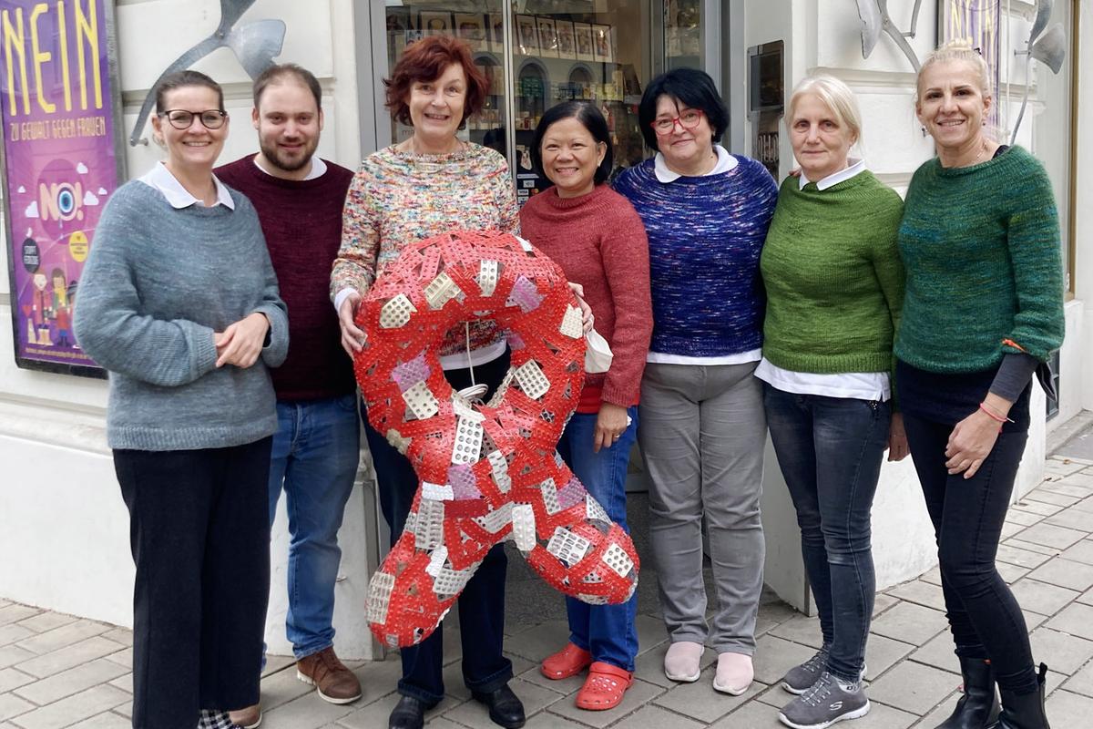 Team der Marien Apotheke mit Mag. pharm. Karin Simonitsch, das einen großen Red Ribbon aus leeren Medikamentenblistern  hält