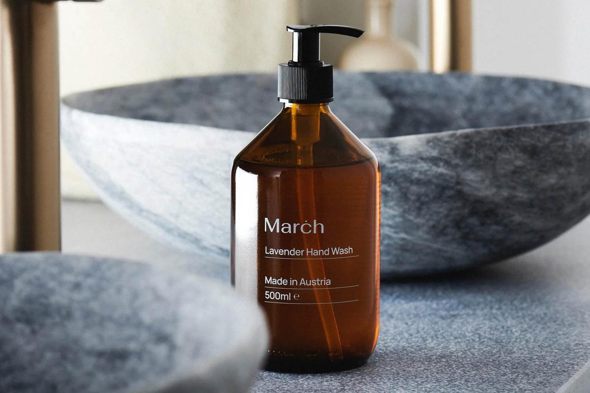 Lavendel-Flüssigseife von MARCH Care in dunkler Glasflasche neben einem Marmor-Waschbecken