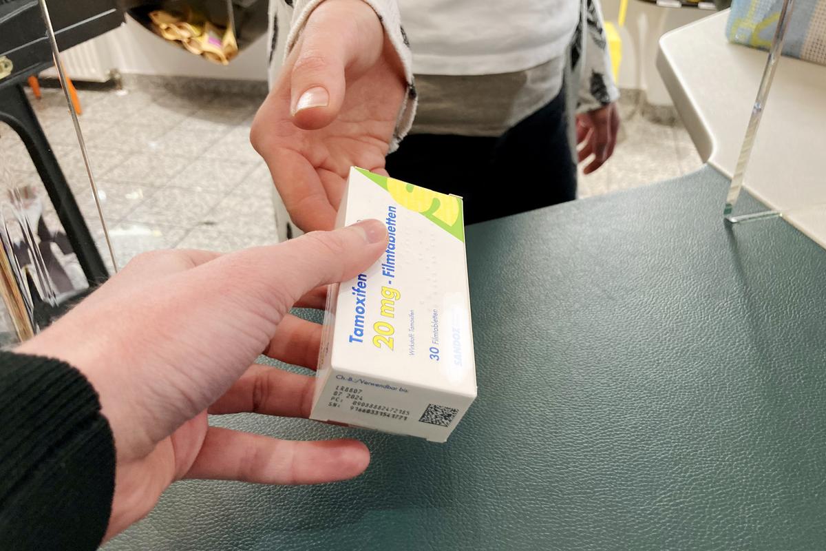 Symbolbild von einer Packung Tamoxifen, die von einer Apothekerin an eine Kundin übergeben wird